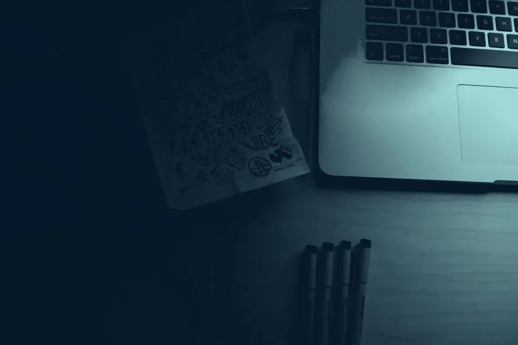 A desk with a laptop and notes, lit from one side